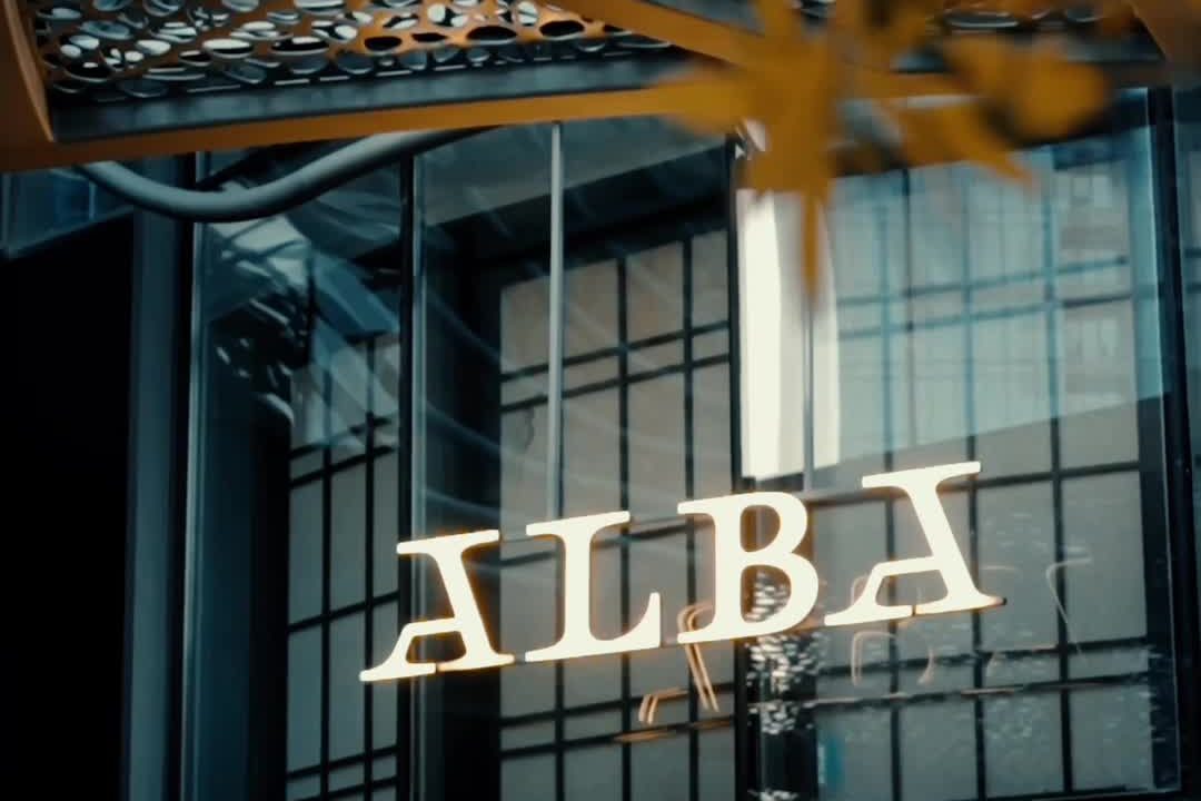The entrance to Alba on Dubai Opera Plaza: a lattice façade with the ALBA lettering above the door and a brass disc beside it.