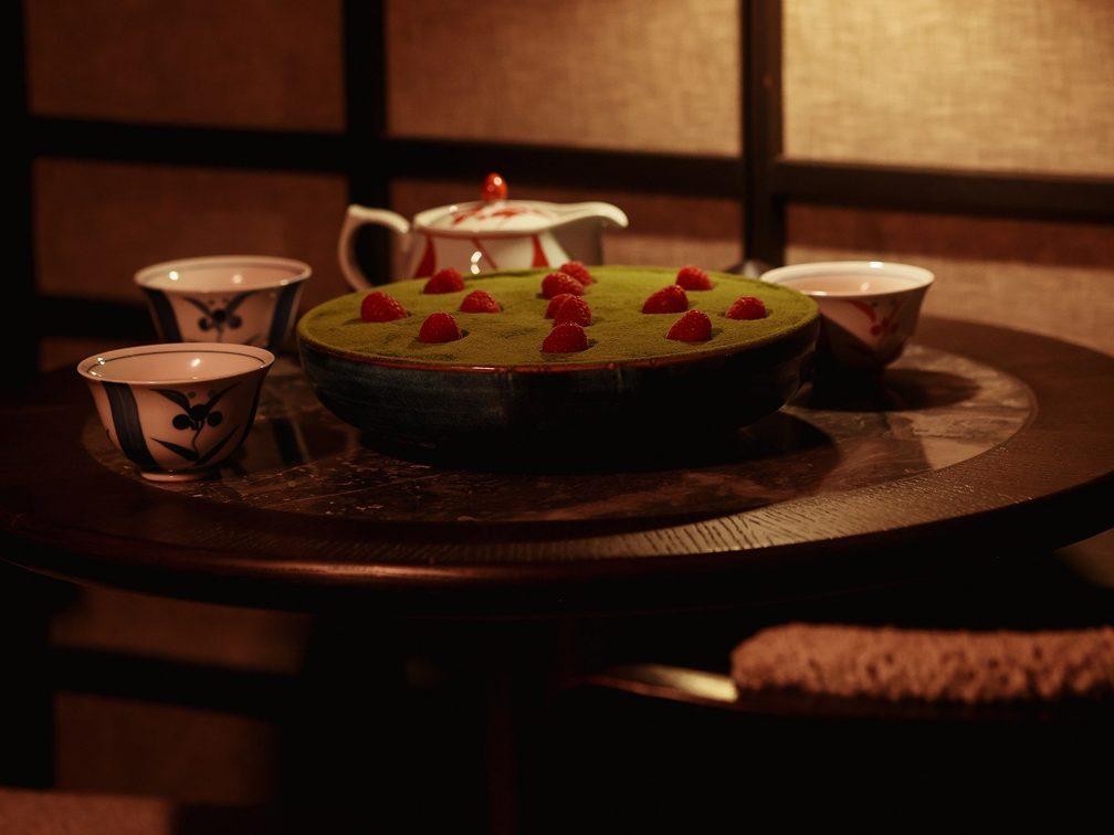 A matcha dessert on a low table with a teapot and two cups beside it.