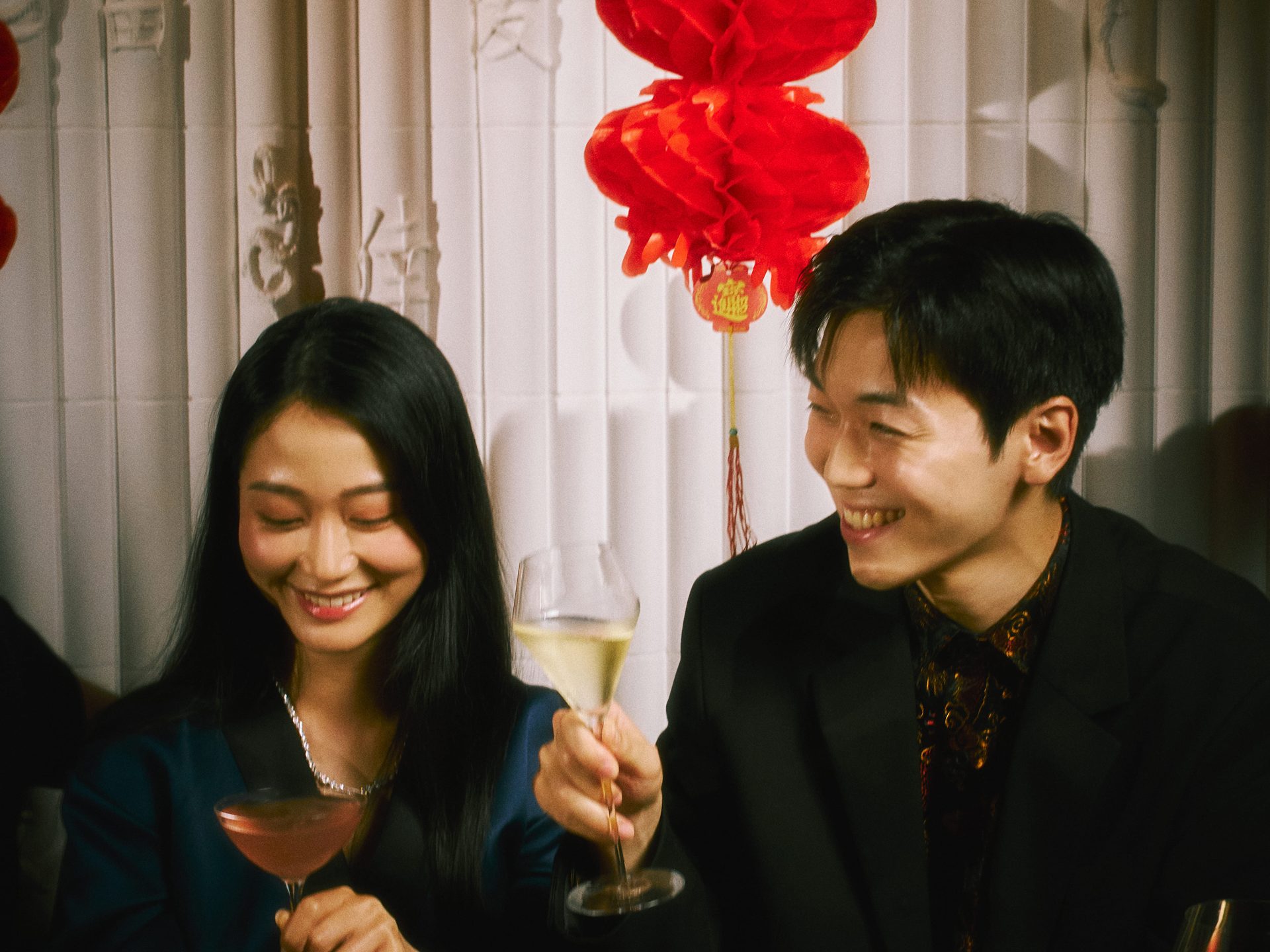 Two guests at Alba raising champagne flutes across a laid table.