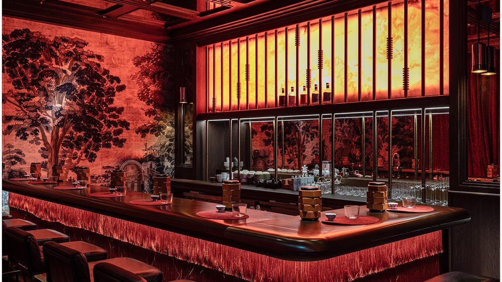The red-lit bar room inside the Alba building, stools drawn up to the counter.